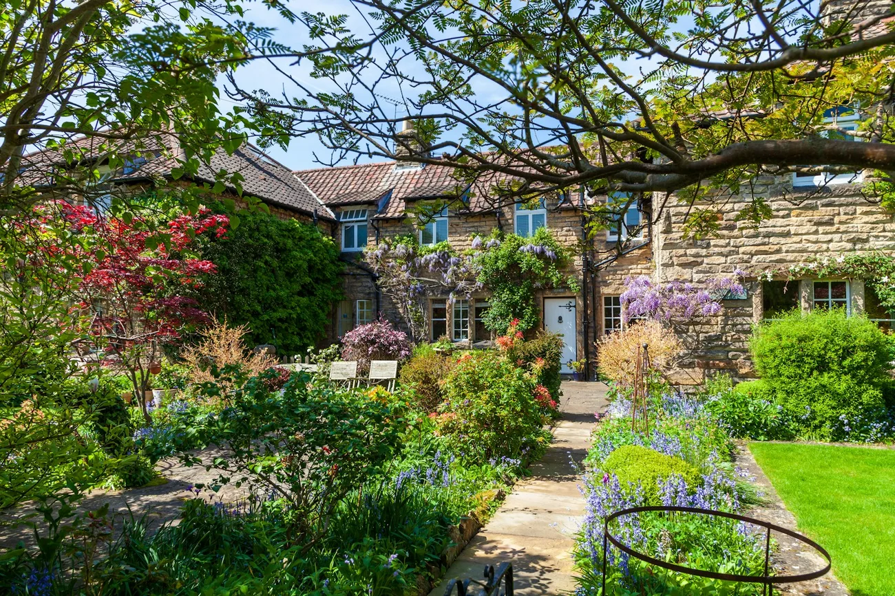 A well-maintained British garden with flowering borders and mature greenery